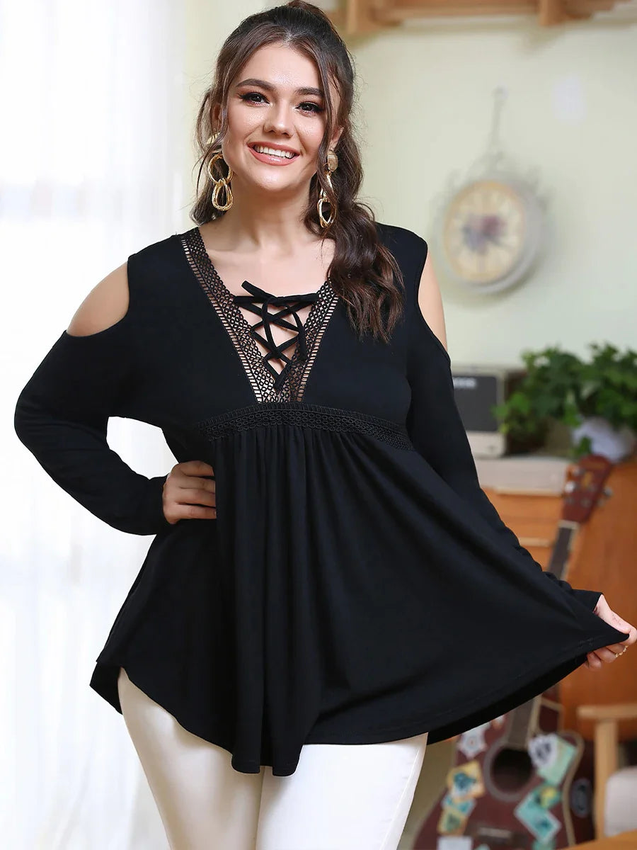 Frau in schwarzer, schulterfreier Bluse mit Spitzenbesatz, lächelnd, modisch, elegant.