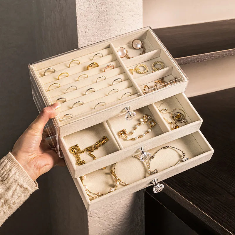 Transparente Schmuckbox mit Fächern, gefüllt mit goldenen Ringen und Armbändern, aufbewahrung.