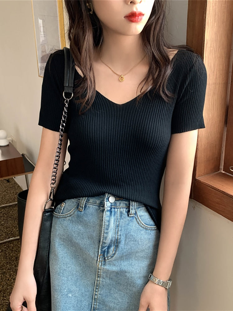 Frau in schwarzem, geripptem V-Ausschnitt-Shirt und blauer Jeans, modisch, lässig, elegant.