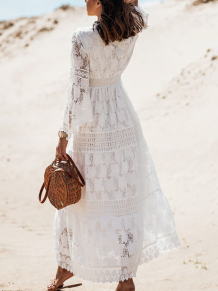Frau in weißem Spitzenkleid am Strand mit brauner Korbtasche, Sommermode, Boho-Stil.