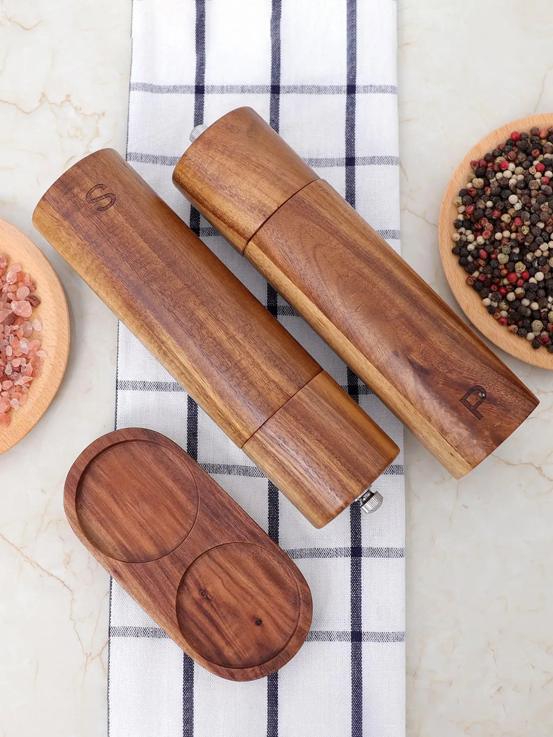Salz- und Pfeffermühlen aus Holz, graviert, auf kariertem Tuch, mit rosa und buntem Pfeffer.