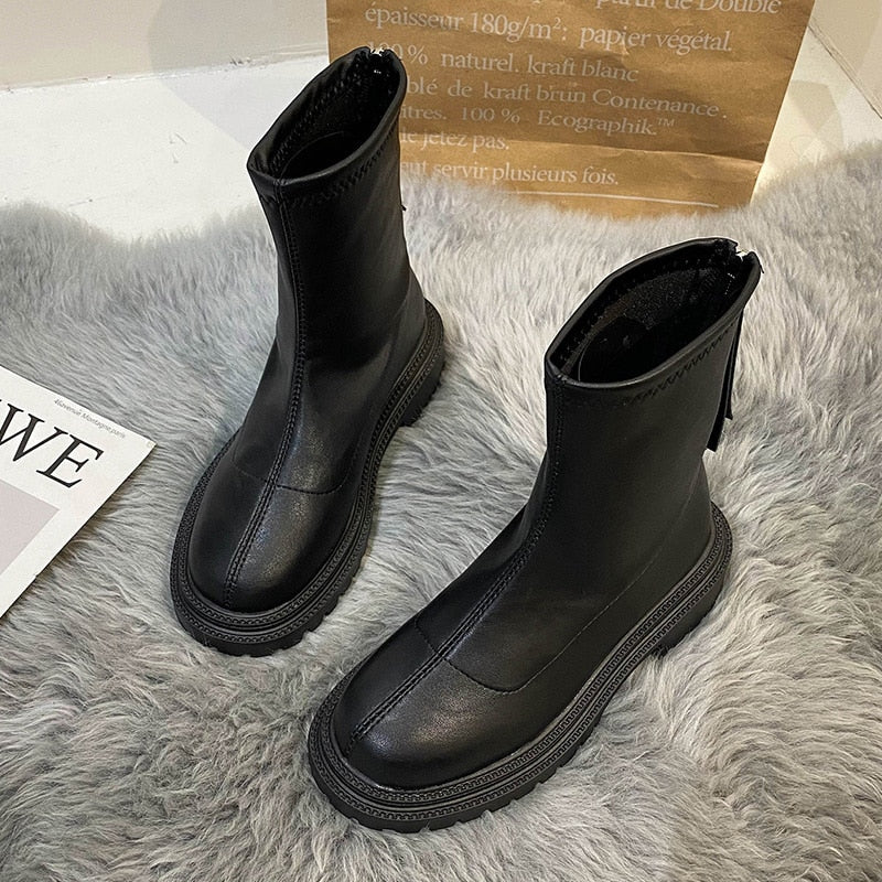 Schwarze Lederstiefel mit Reißverschluss, modisch, robust, auf grauem Teppich.