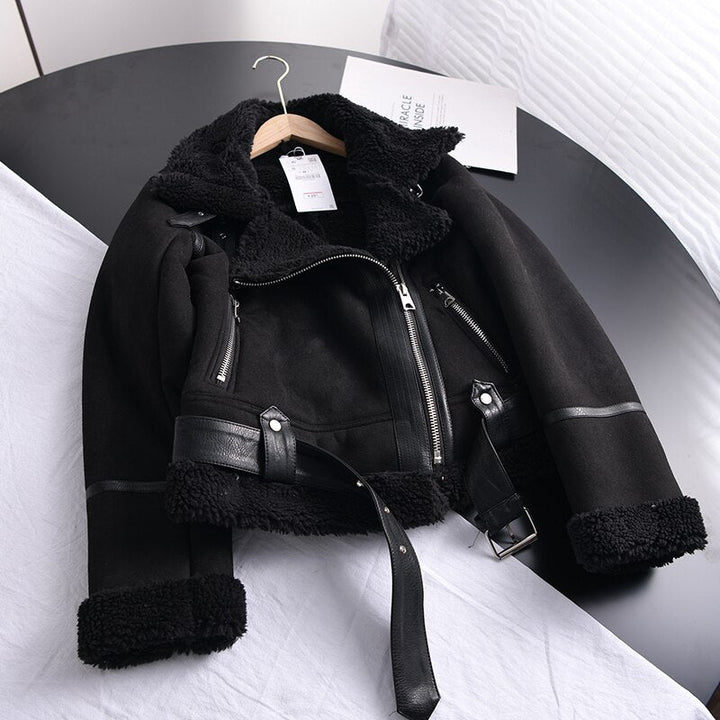 Schwarze Bikerjacke aus Leder mit Fellfutter, Reißverschluss und Gürtel auf Tisch.