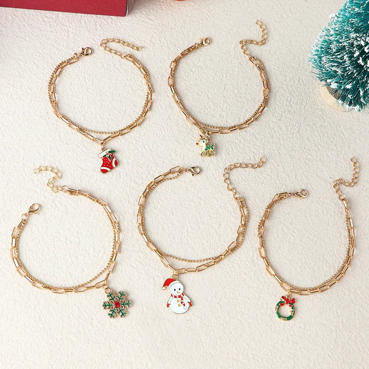 Fünf goldene Weihnachtsarmbänder mit Anhängern: Schneemann, Kranz, Schneeflocke, Stiefel, Baum.