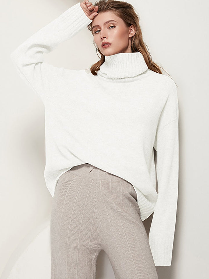 Frau in weißem Rollkragenpullover und grauer Hose, modisch, elegant, Herbstmode.