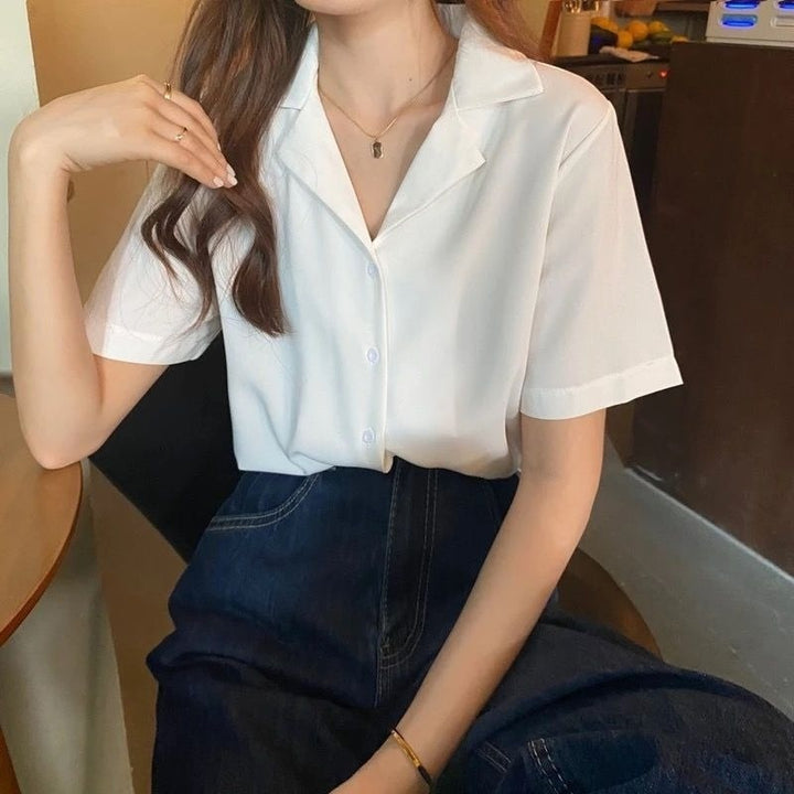Frau in weißer Bluse und dunkelblauem Rock, sitzt an Tisch, modisch, elegant, Freizeitkleidung.