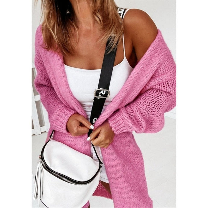 Frau in rosa Strickjacke mit weißem Top und weißer Umhängetasche, modisch, lässig.