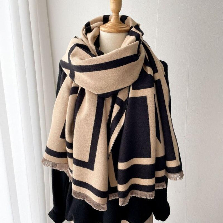 Beige und schwarzer Wollschal mit geometrischem Muster auf Kleiderbüste, modisches Accessoire.
