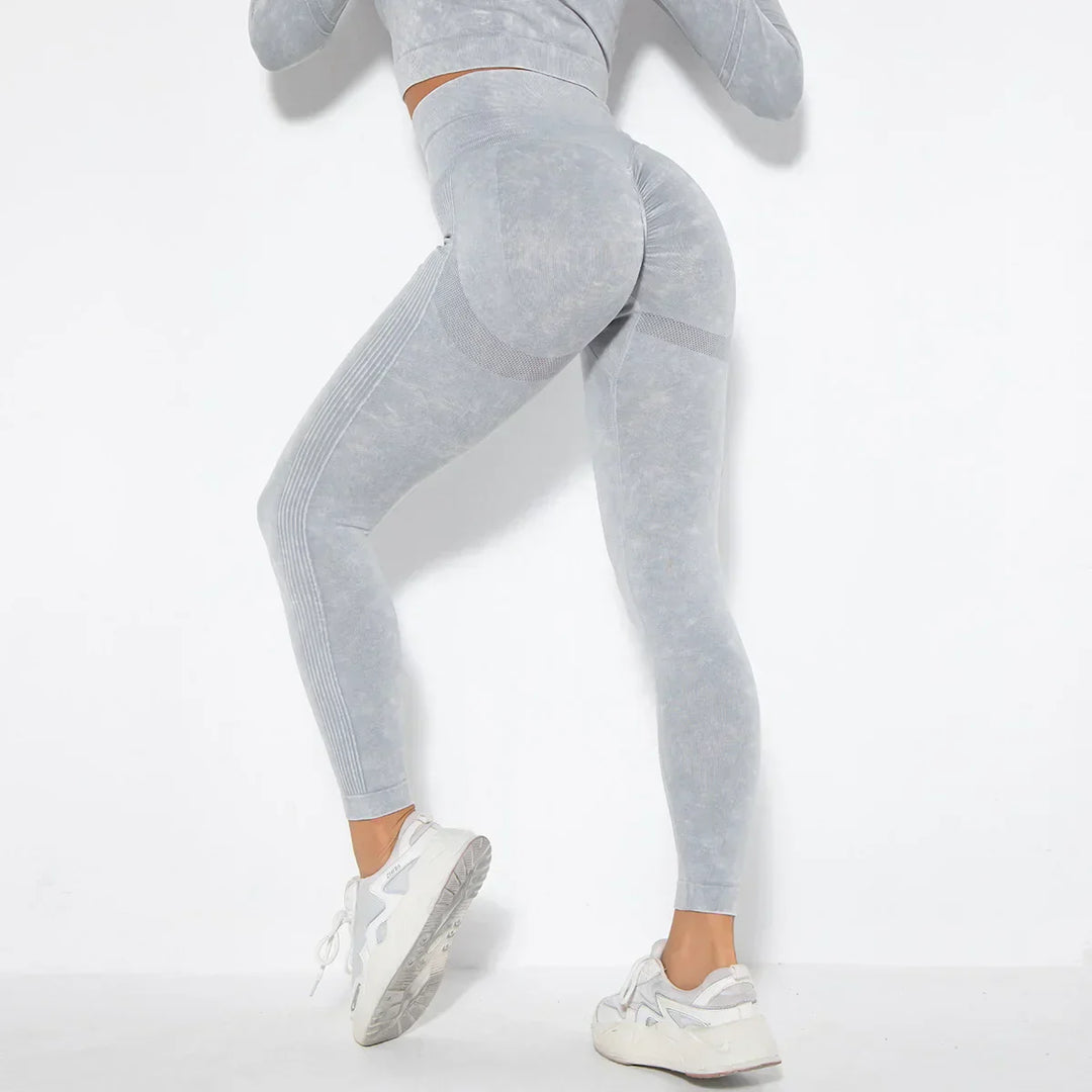 Frau in grauer Sportleggings und Sneakers, Fitnessmode, nahtlos, elastisch, für Workout.
