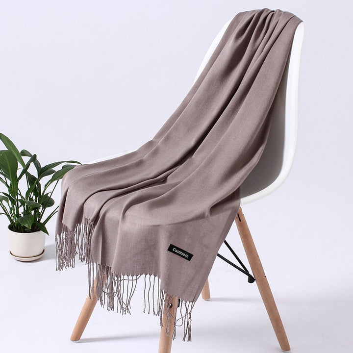 Beiger Kaschmirschal auf Stuhl, weiches Material, modisches Accessoire, Wohnzimmer-Dekoration.