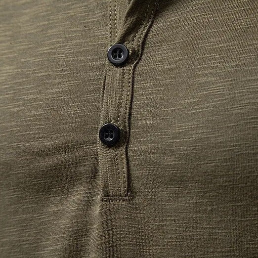 Detail knoflíkové légy olivově zeleného Henley trika s černými knoflíky a prošíváním kolem plisé. 7
