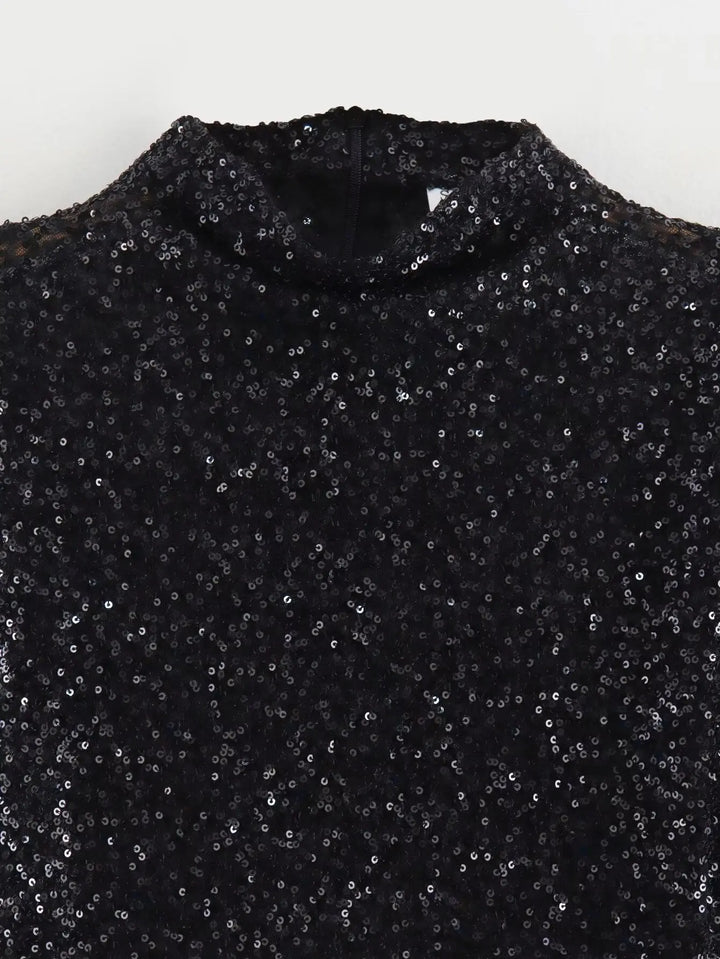 Detail černé flitrové látky u stojatého límce, produkt rozložený bez modelky 4