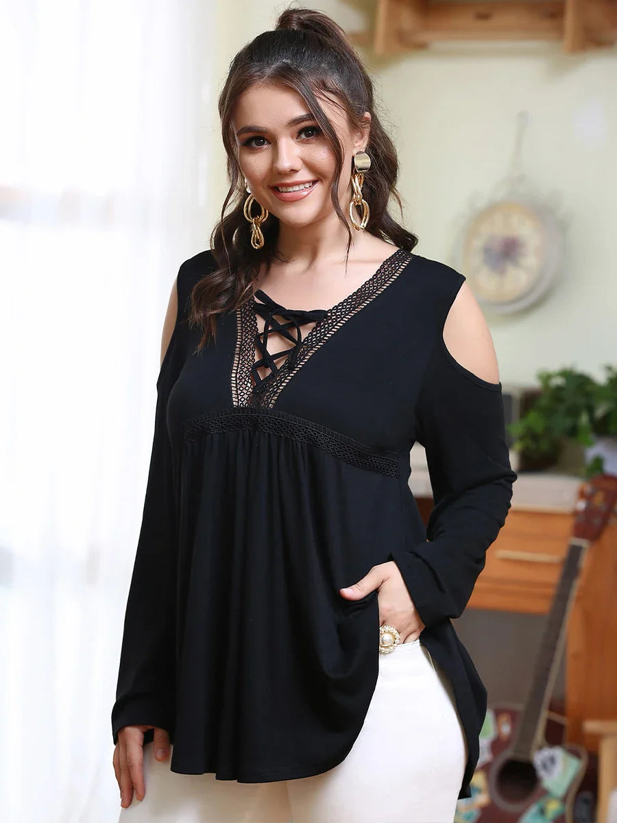 Frau in schwarzer, schulterfreier Bluse mit Spitzenbesatz, lächelnd, modisch, elegant.