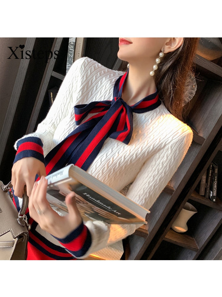 Frau in weißem Strickpullover mit rotem und blauem Band, hält Buch, elegante Mode.