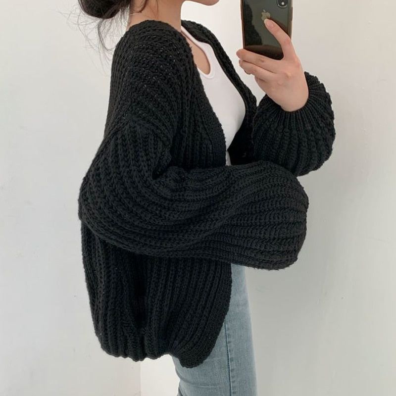 Frau trägt schwarzen Strick-Cardigan, übergroß, mit weißen Top und blauen Jeans.