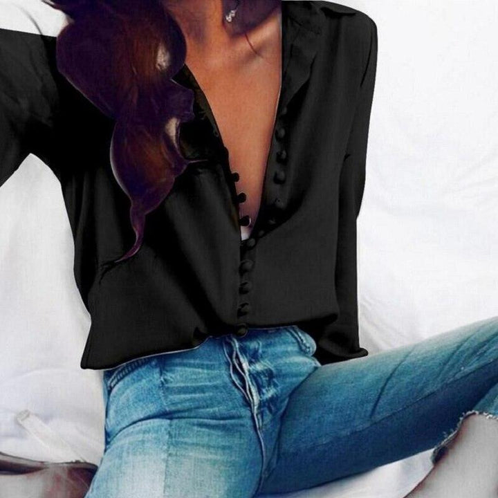 Frau in schwarzer Bluse mit Knopfleiste und blauen Jeans, modisch, elegant, Freizeitkleidung.