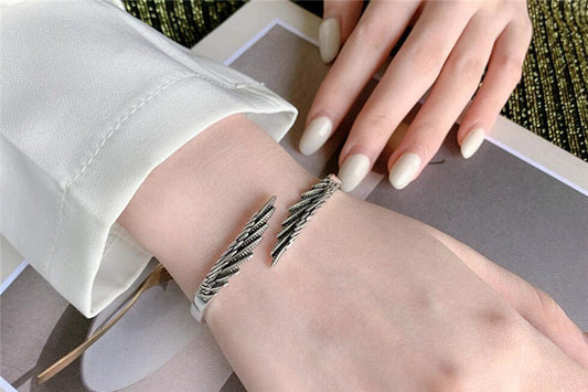 Silbernes Armband mit Blattdesign, Damenmode, eleganter Schmuck, Nahaufnahme, Handgelenk.