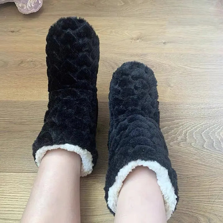 Schwarze Plüsch-Hausschuhe auf Holzboden, gemütlich, warm, Damenmode, Winteraccessoire.