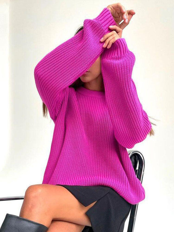 Frau in pinkem Strickpullover, sitzt auf Stuhl, modisch, Herbstmode, Damenbekleidung.