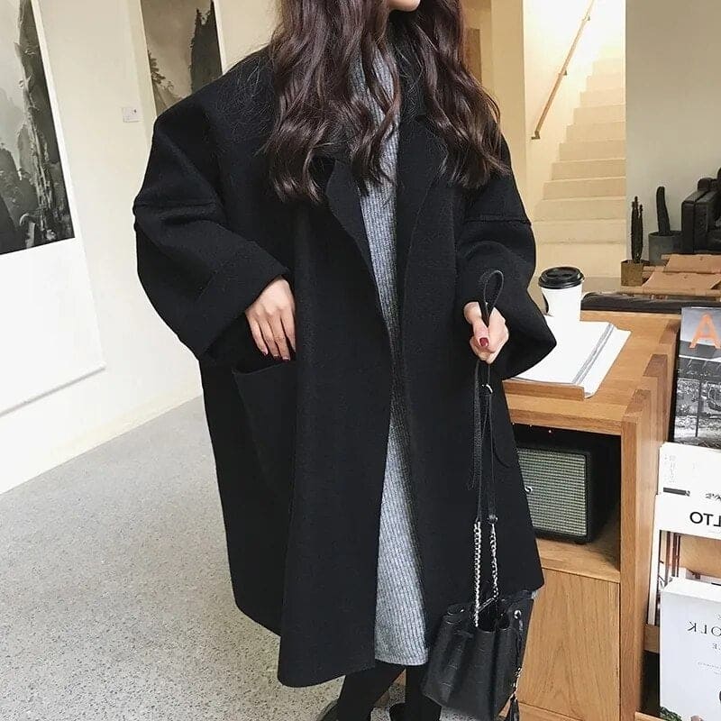 Frau in schwarzem Wollmantel, graues Kleid, modisch, Herbstmode, Innenraum, stilvoll.