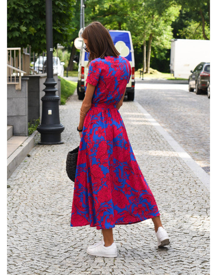 Frau in rotem, geblümtem Maxikleid auf gepflasterter Straße, Sommermode, Rückansicht.