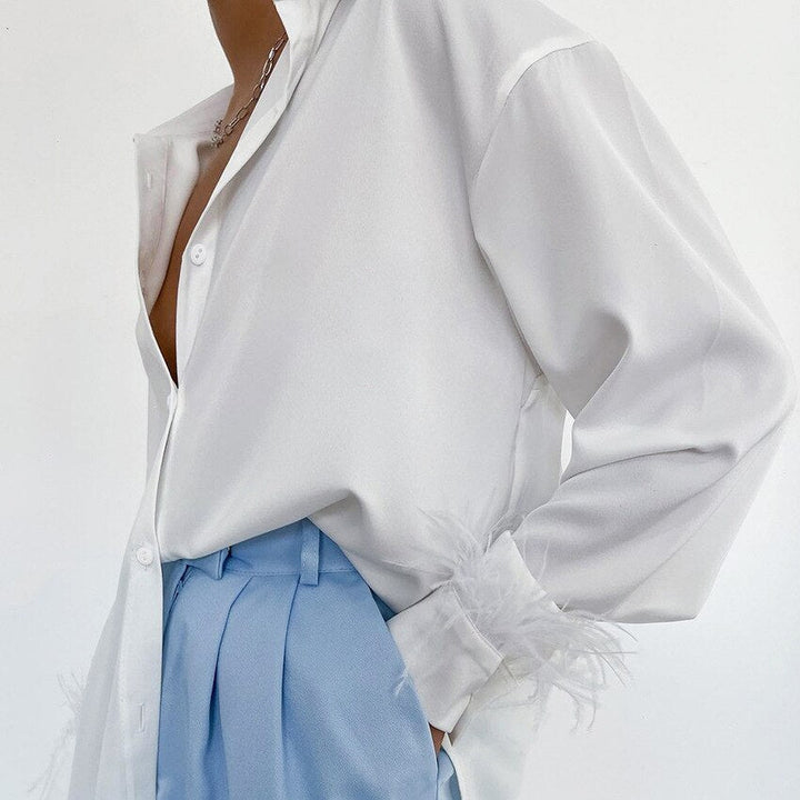 Weiße Bluse mit Federn, hellblaue Hose, elegante Damenmode, stilvolles Outfit.