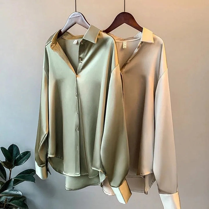 Zwei seidene Blusen in Grün und Beige auf Kleiderbügeln, elegante Damenmode, langärmlig.