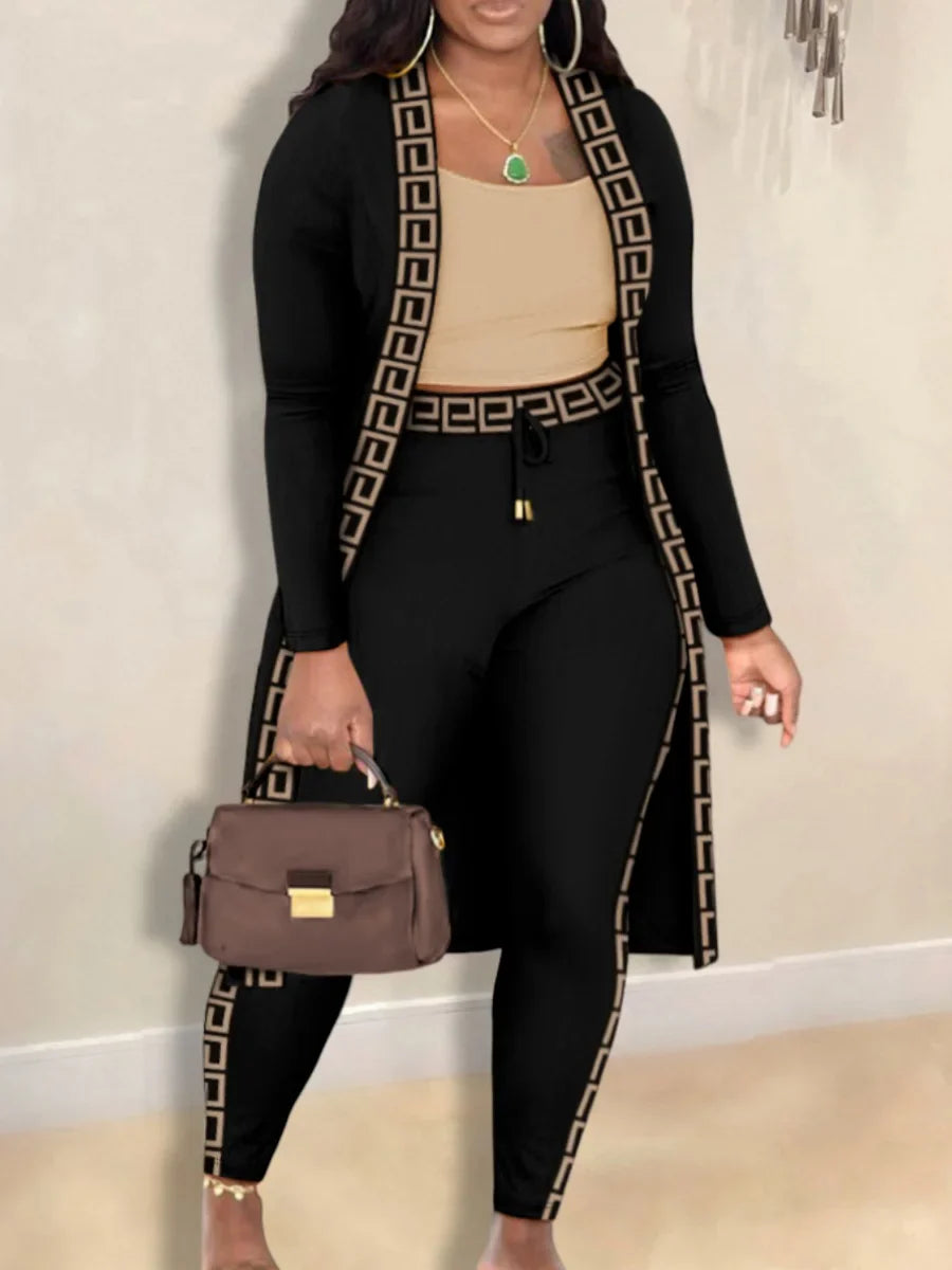 Frau in schwarzem Zweiteiler mit griechischem Muster, braune Handtasche, elegantes Outfit.