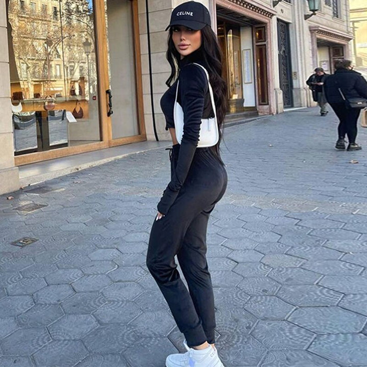 Frau in schwarzem Trainingsanzug und Celine-Cap auf Stadtstraße, modisch, sportlich, urban.