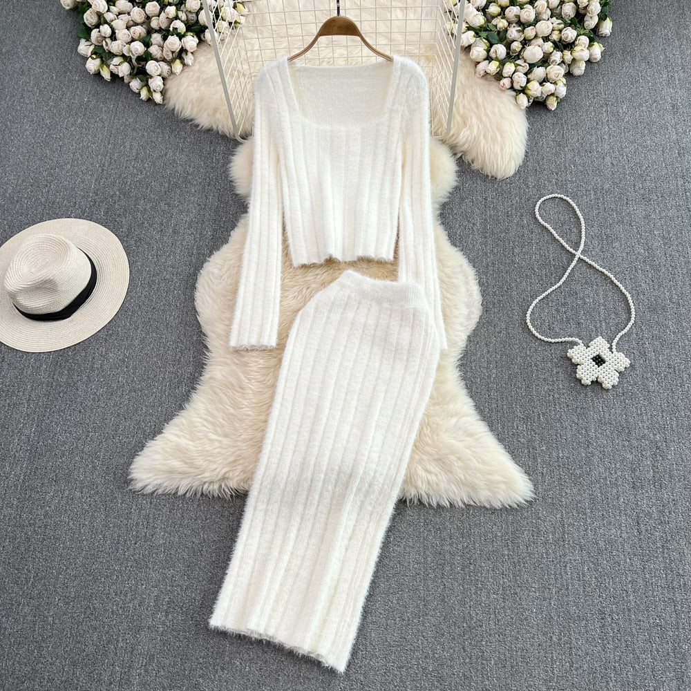 Weißes Strick-Zweiteiler-Set aus Pullover und Rock auf Teppich, elegantes Damen-Outfit.