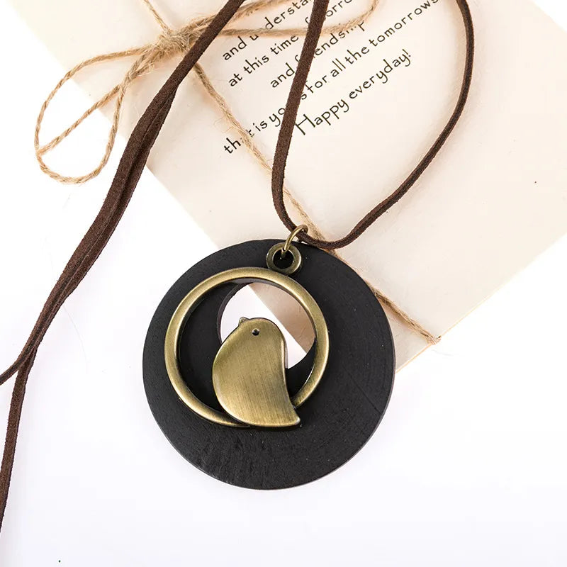 Runder Holzanhänger mit Messingvogel, braunes Lederband, handgefertigter Schmuck, Geschenkidee.