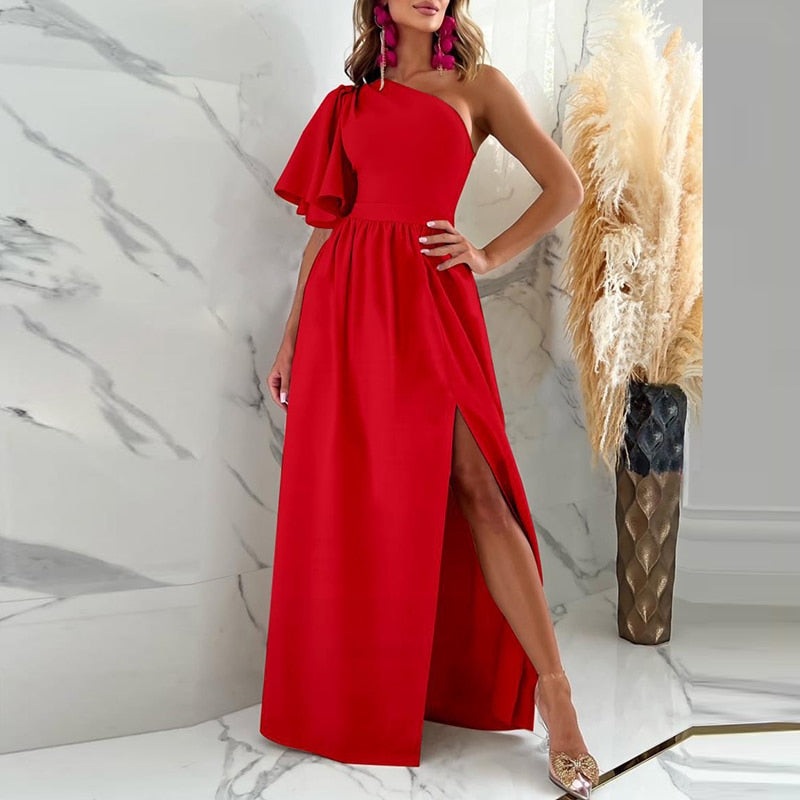 Frau im eleganten roten Abendkleid mit asymmetrischem Schnitt und hohem Schlitz, Marmorhintergrund.