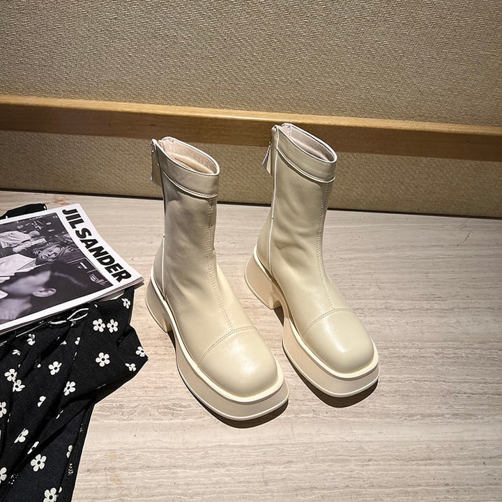 Beige Damenstiefel aus Leder mit Reißverschluss, modisch, elegant, auf Holztisch.