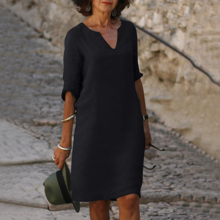 Frau in schwarzem Kleid auf Kopfsteinpflasterweg, elegantes Design, Freizeitmode.