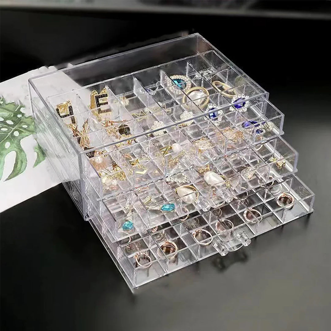 Klarer Acryl-Schmuck-Organizer mit mehreren Fächern für Ohrringe und Ringe auf schwarzem Tisch.