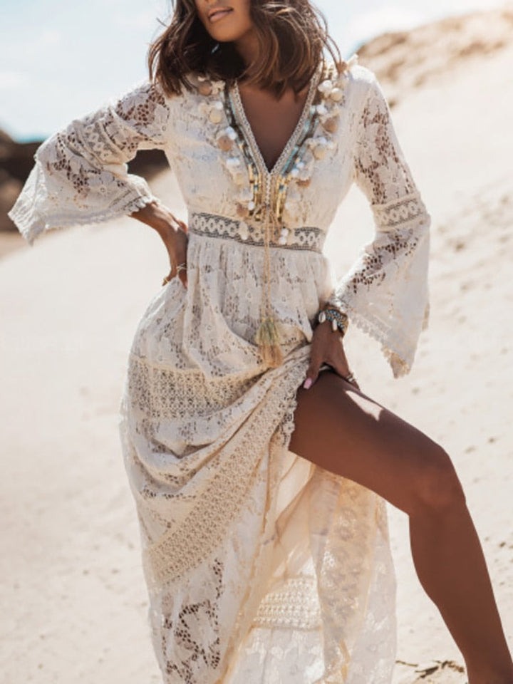 Frau in weißem Spitzenkleid mit V-Ausschnitt und Quasten, Strandhintergrund, Sommermode.