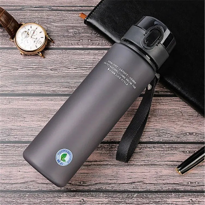 Graue Edelstahl-Wasserflasche mit Deckel, 500ml, auf Holztisch, ideal für Outdoor-Aktivitäten.