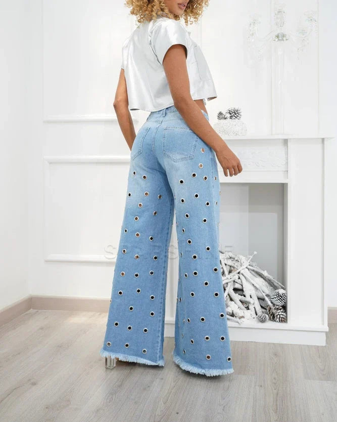 Frau in blauer Schlaghose mit Cut-Outs, weißes Top, modisch, trendige Damenbekleidung.
