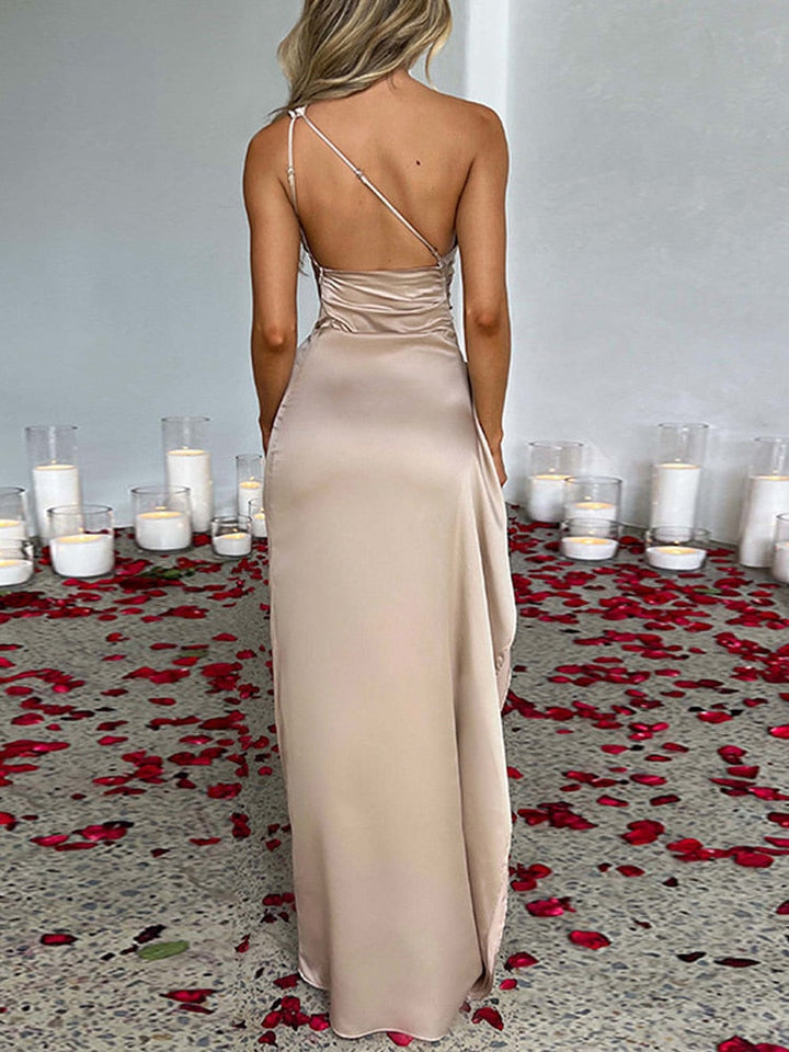 Frau im eleganten, beigen Abendkleid mit Kerzen und Rosenblättern auf dem Boden.
