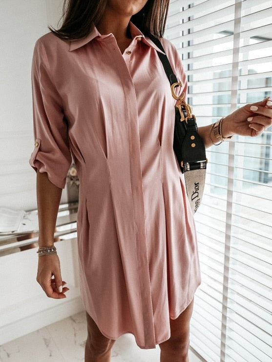 Frau in rosa Hemdkleid mit schwarzer Umhängetasche, elegantes Outfit, modernes Design.