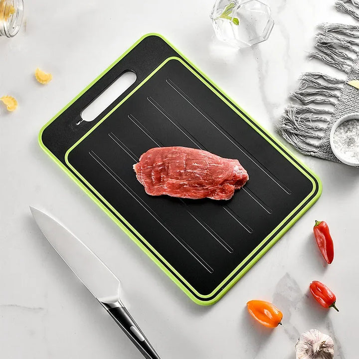 Schwarzes Schneidebrett mit grünem Rand, rohes Fleisch, Küchenmesser, Paprika, Marmorhintergrund.