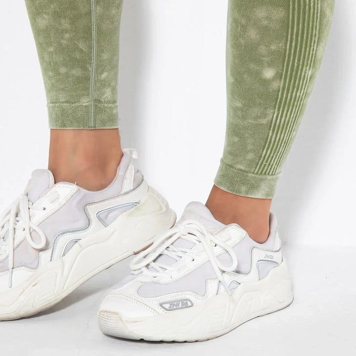 Weiße Sneaker Damen, sportlich, mit grüner Leggings, bequem, modisch, Freizeitkleidung.