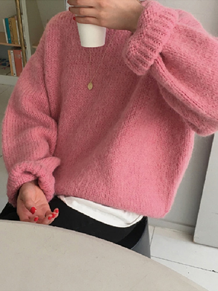 Person in rosa Strickpullover hält weißen Becher, gemütliche Wintermode, lässiger Stil.