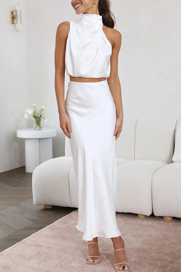 Frau in weißem Satin-Zweiteiler, ärmelloses Top, langer Rock, elegantes Abendoutfit.