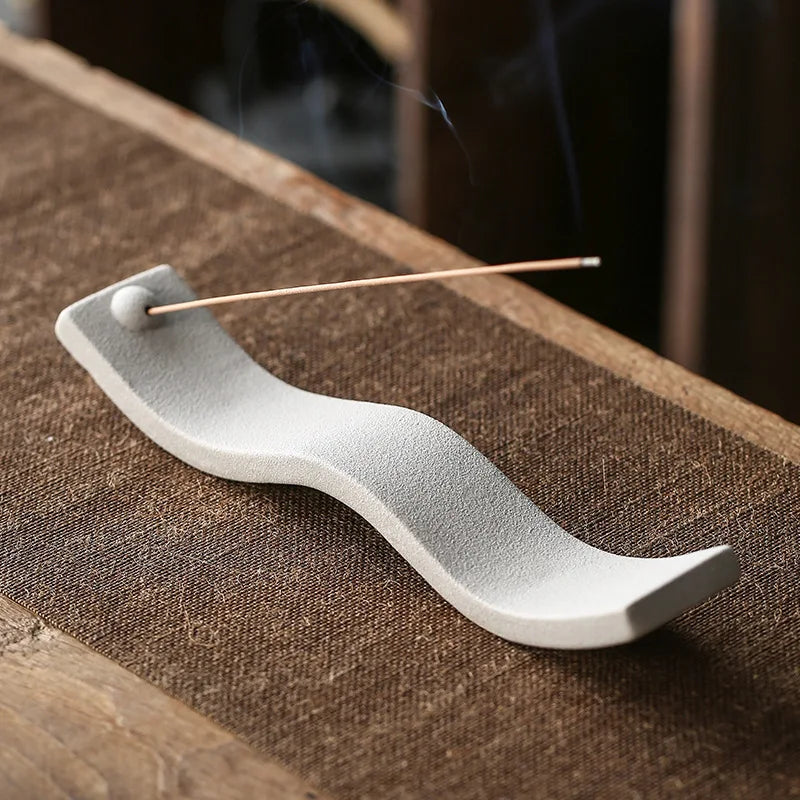 Wellness Keramik-Räucherstäbchenhalter, wellenförmig, grau, auf Holztisch.