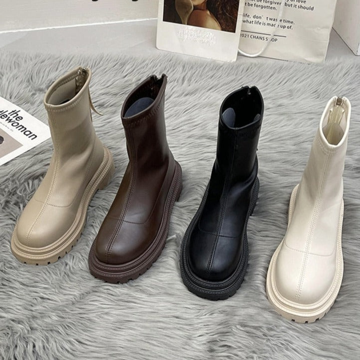 Vier Paar Damenstiefel, beige, braun, schwarz, creme, auf grauem Teppich, modisch, elegant.