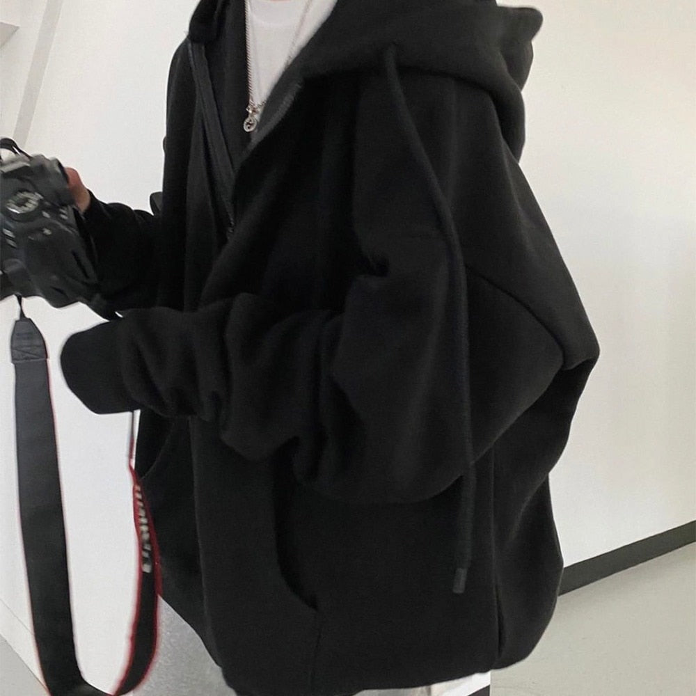 Person in schwarzem Hoodie mit Kamera, lässiger Stil, Fotografie, Mode, Freizeitkleidung.