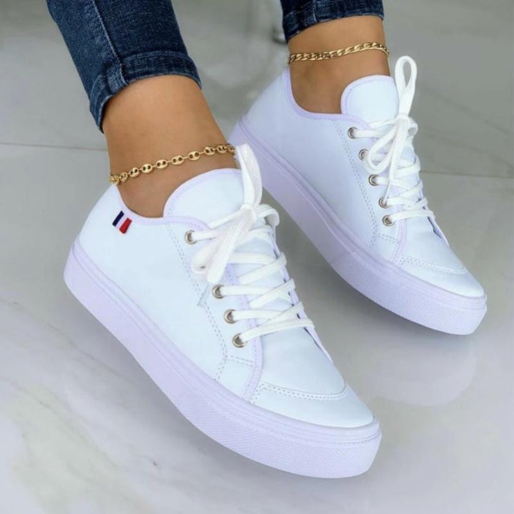 Weiße Damen-Sneaker aus Leder mit goldener Knöchelkette, modisch und bequem.