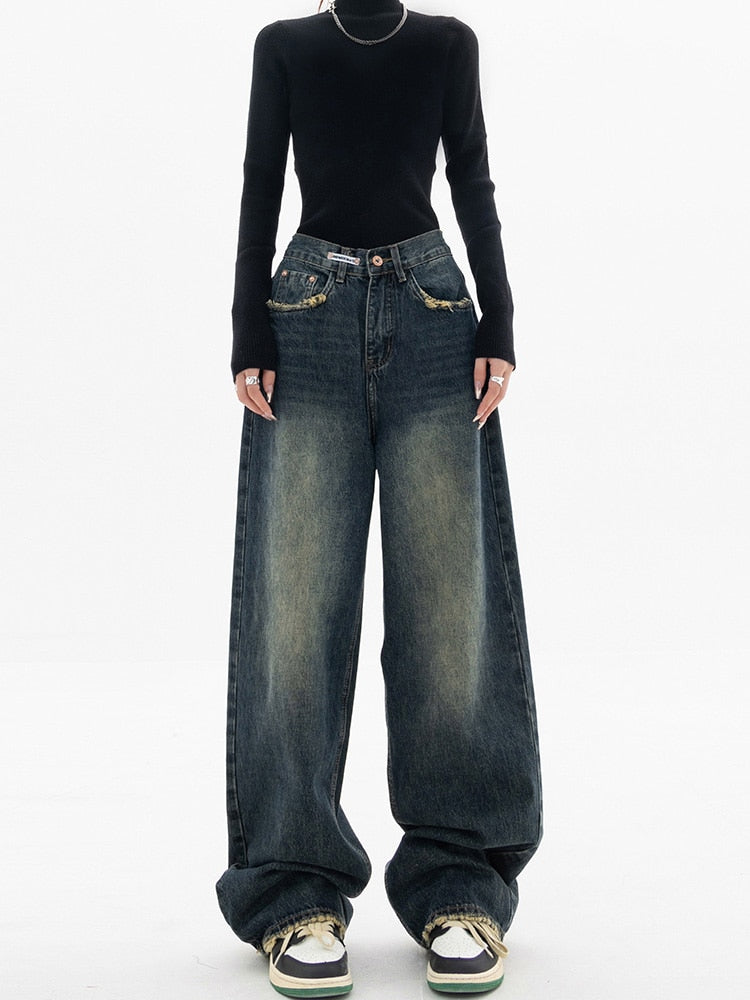 Frau in schwarzem Pullover und weiten Jeans, modische Streetwear, lässiger Stil.