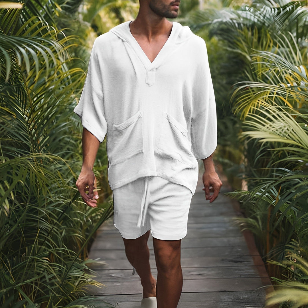 Mann in weißem Kapuzenpullover und Shorts, Spaziergang im tropischen Garten.